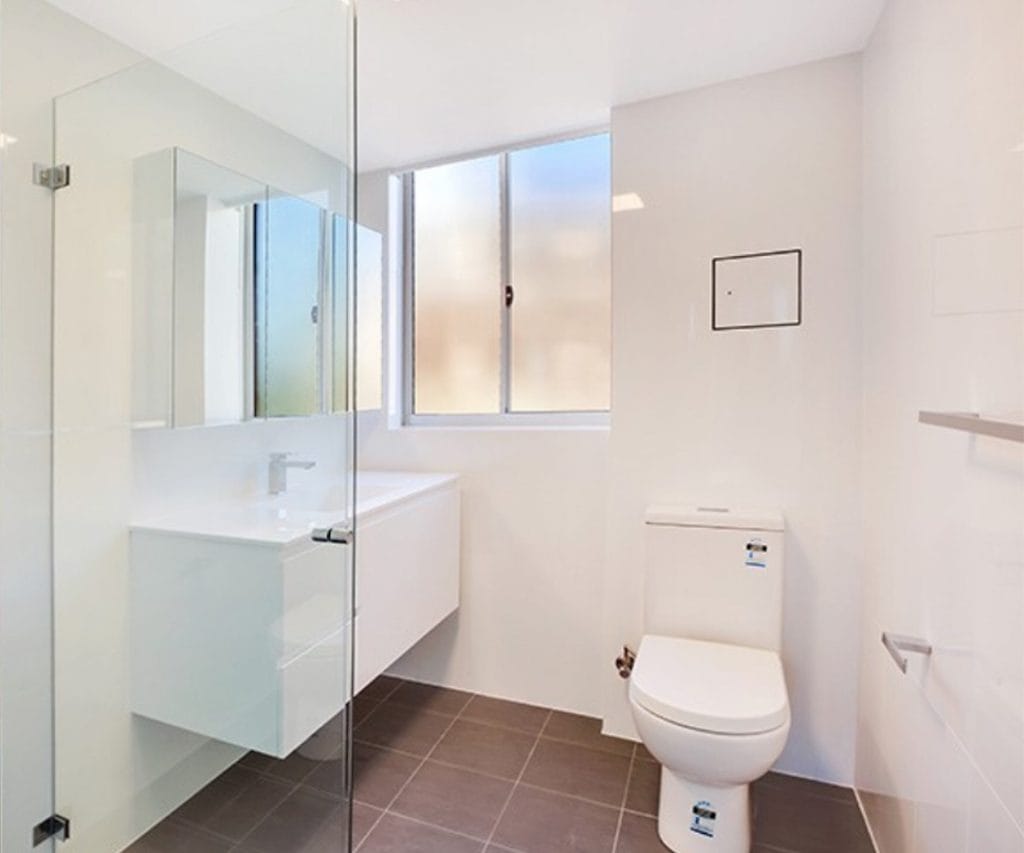 Modern small bathroom renovation in Sydney with white vanity, glass shower screen and toilet