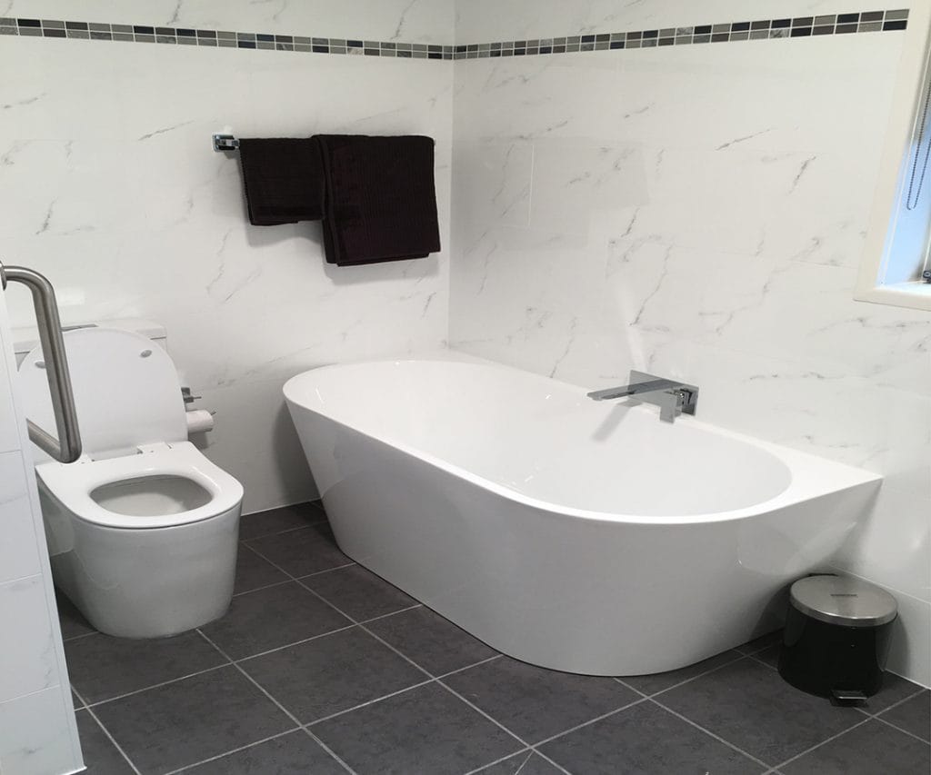 Completed bathroom renovation in Sydney with freestanding bathtub, marble-look wall tiles and grey floor tiles